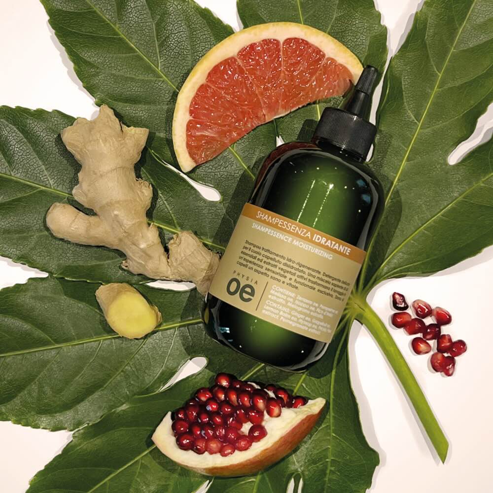Immagine di uno shampoo idratante con sfondo naturale, ove sono collocati zenzero, melograno e arancia