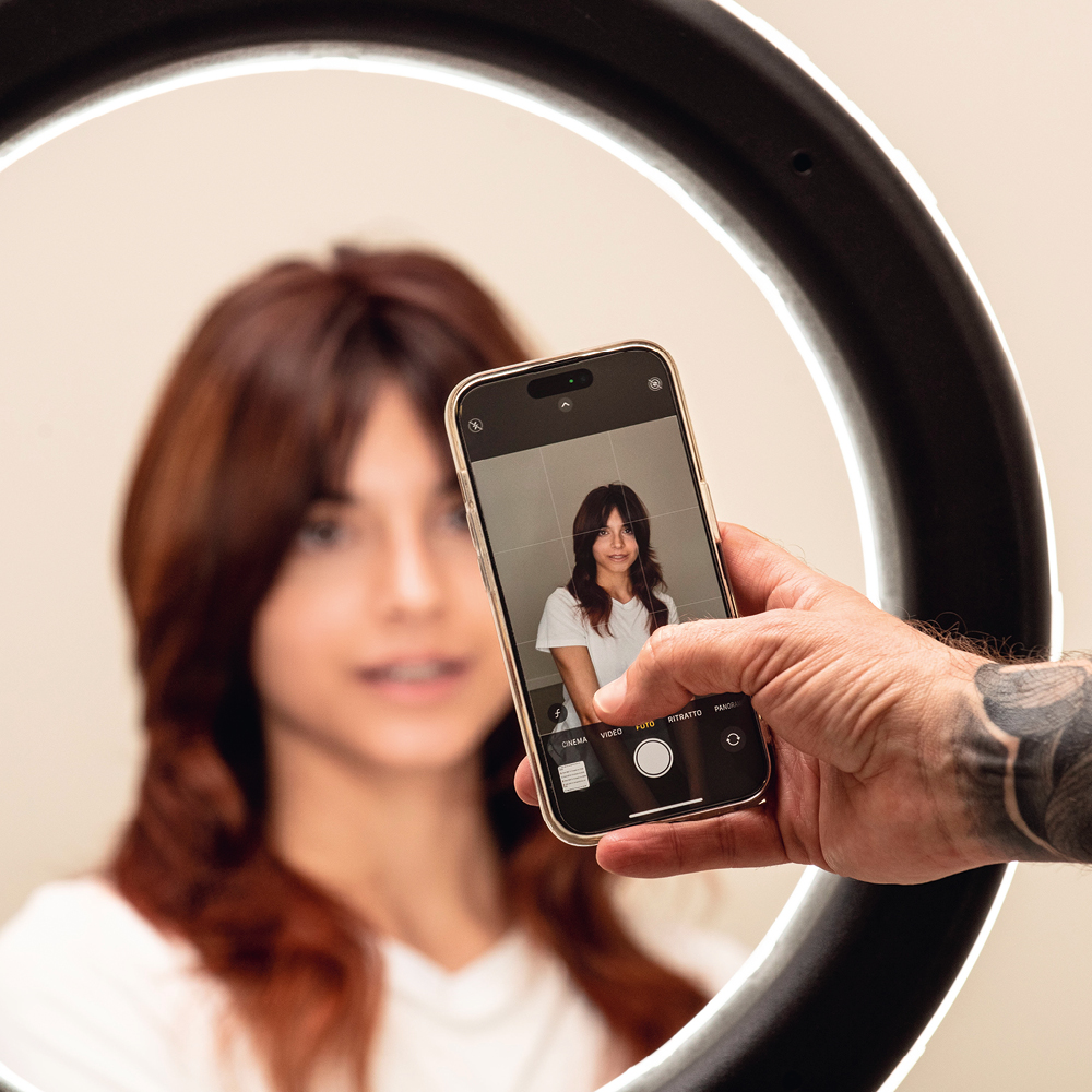 Immagine di una mano con un iPhone mentre scatta una foto ad una modella